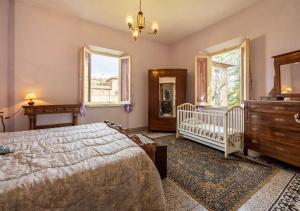 a bedroom with a bed and a crib and windows at 15 min da Montepulciano - Villa Chiara in Montefollonico