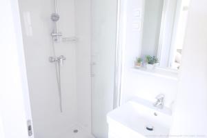 La salle de bains blanche est pourvue d'une douche et d'un lavabo. dans l'établissement Mobilheim Mate2, à Nin