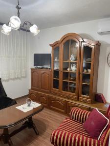 ein Wohnzimmer mit einem großen Holzschrank und einem Tisch in der Unterkunft Smeštaj Zeka Tekija in Tekija