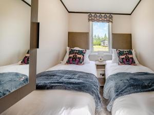 three twin beds in a room with a window at Pheasant Lodge in Nawton