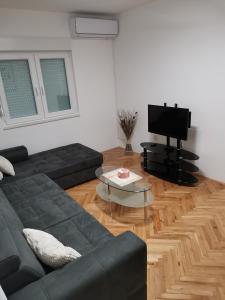 sala de estar con sofá negro y TV en AD Apartman Bileća, en Bileća