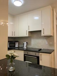 a kitchen with white cabinets and a black counter top at Central-LUXE 1 BR-Kensington-24 7 security-Netflix in London