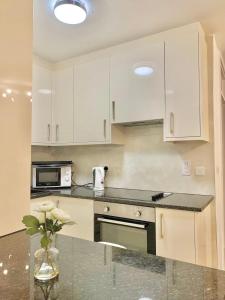 a kitchen with white cabinets and a vase of flowers at Central-LUXE 1 BR-Kensington-24 7 security-Netflix in London
