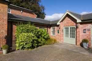 a brick house with a garage with a green door at Beech House in Little Walsingham