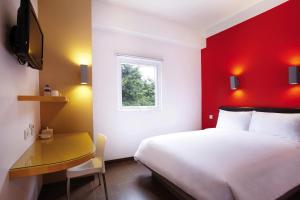 ein Schlafzimmer mit einem weißen Bett und einer roten Wand in der Unterkunft Amaris Hotel Madiun in Madiun