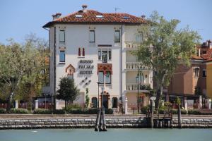 ein großes weißes Gebäude neben dem Wasser in der Unterkunft Hotel Russo Palace in Lido di Venezia