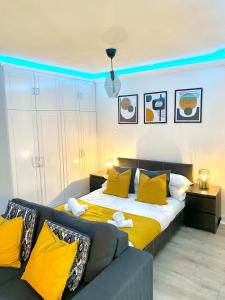 a bedroom with a bed with yellow pillows and a couch at LUXURY Apt - Balcony- Kensington-24 7 security in London