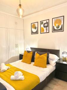 a bedroom with a large bed with yellow pillows at LUXURY Apt - Balcony- Kensington-24 7 security in London