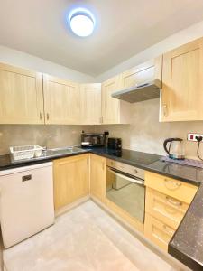 a kitchen with wooden cabinets and black counter tops at LUXURY Apt - Balcony- Kensington-24 7 security in London