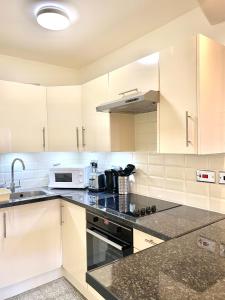 uma cozinha com armários brancos, um lavatório e um micro-ondas em Luxury Apt- Balcony-Kensington- 24 7 security em Londres