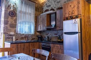 cocina con armarios de madera y nevera blanca en Traditional Mansion, en Kaláthenai