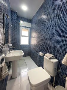 een blauw betegelde badkamer met een toilet en een wastafel bij HOSTAL MH BORJ in Martil