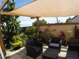 un patio con sillas y una sombrilla de madera en La Villa Vie d'Hôte en Saint-Denis