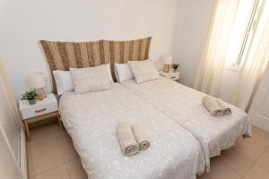 Un dormitorio con una cama blanca con toallas. en Pedregalejo Madueño 10, en Málaga