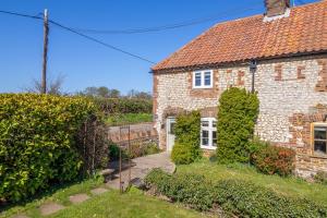 une vieille maison en briques avec du lierre qui s'élève autour d'elle dans l'établissement Orchard Cottage, à Ringstead