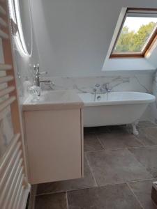 a bathroom with a tub and a sink and a window at La Suite in Vron