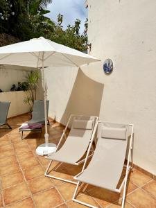 two chairs and an umbrella on a patio at El Arenal Townhouse By The Beach With Swimming Pool - EaW Homes in Marbella