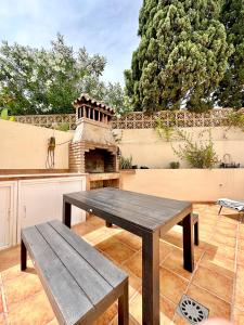a wooden picnic table on a patio with a fireplace at El Arenal Townhouse By The Beach With Swimming Pool - EaW Homes in Marbella