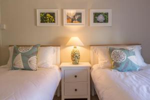 a bedroom with two beds and a lamp on a night stand at Mulberry Cottage in Wells next the Sea