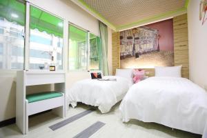 een slaapkamer met 2 bedden, een bureau en een raam bij Clover house-自助式無人旅店 in Zhongli