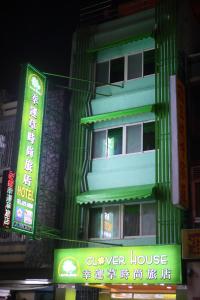een hoog groen gebouw met borden ervoor bij Clover house-自助式無人旅店 in Zhongli