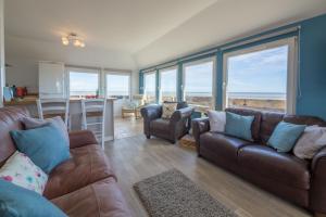 a living room with couches and a kitchen with windows at Wyndham Beach House in Walcott