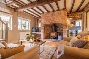 a living room with a fireplace and a brick wall at Stockmans Cottage in Foulsham