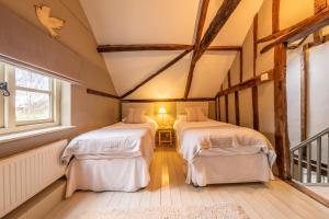 2 camas en una habitación con 2 ventanas en Stockmans Cottage, en Foulsham