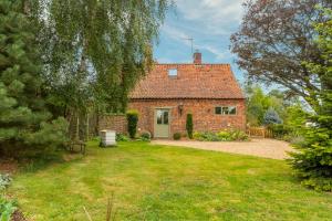 an old brick house with a grass yard at Stockmans Cottage in Foulsham