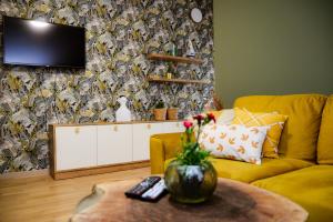uma sala de estar com um sofá amarelo e uma televisão em Green Home - Lamela 1 Tivat em Tivat