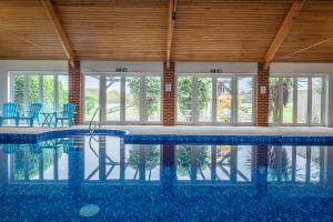 una gran piscina con sillas azules y ventanas en The Heydon, en Roughton