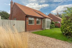 a brick house with a fence and grass at Dolphin in Burnham Market