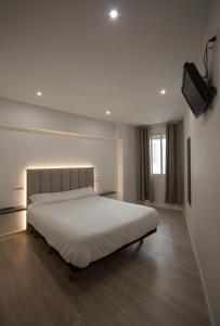 1 dormitorio con 1 cama blanca grande y TV en Hotel Marín, en Marín
