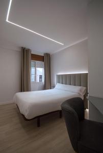 a bedroom with a large bed and a chair at Hotel Marín in Marín