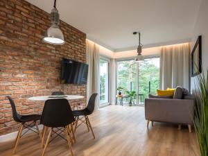 a living room with a brick wall and a table and chairs at VacationClub – Sosnowa 4 Apartament 5 in Mielno