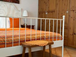 ein weißes Bett mit einem Holzhocker im Schlafzimmer in der Unterkunft Appartamento Arancione in Menaggio