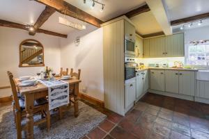 uma cozinha com armários brancos e uma mesa e cadeiras em Newgates Cottage em Wells-next-the-Sea