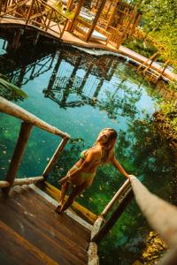a woman standing on the edge of a pool of water at Hotel Shibari - Restaurant & Cenote Club in Tulum