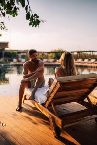 a man and a woman sitting on a bench by the water at Hotel Shibari - Restaurant & Cenote Club in Tulum