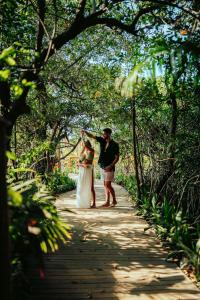 a man and a woman standing on a wooden path at Hotel Shibari - Restaurant & Cenote Club in Tulum