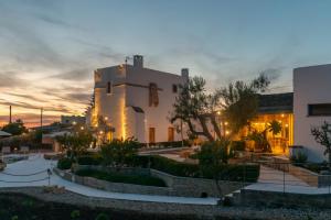 a white building with a sunset in the background at Masseria Samenti in Torre Suda