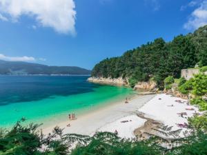 a beach with a group of people in the water at Apartamento Piscina 2G by Urraca Suites Viveiro in Viveiro