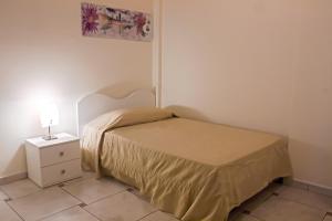 um pequeno quarto com uma cama e uma mesa de cabeceira em Appartamento Ghalà em Galatone
