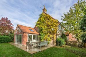 uma casa com uma mesa e cadeiras no quintal em Owl Cottage Woodside em Burnham Market