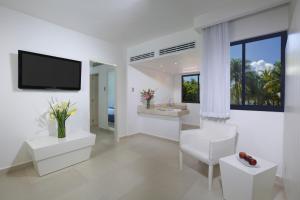 a white bathroom with a tv on a wall at Grand Oasis Tulum Riviera - All Inclusive in Akumal