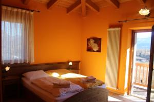 a bedroom with a bed with yellow walls and a window at Maso Fiorini in Rovereto