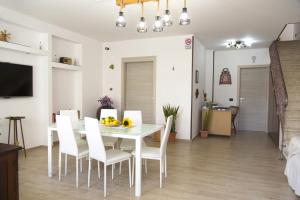 - une salle à manger et un salon avec une table et des chaises blanches dans l'établissement B&B Piano di Sopra, à San Vito Lo Capo