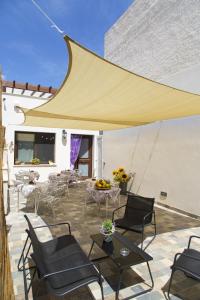 a patio with chairs and tables and a yellow umbrella at B&B Piano di Sopra in San Vito lo Capo