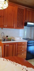 a kitchen with wooden cabinets and a sink and a stove at Apartma Sabatuš in Bohinj +4 photos