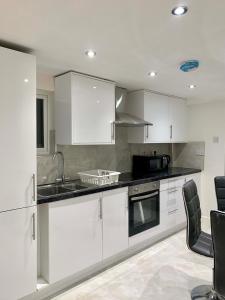 una cucina con armadietti bianchi e ripiani neri di Private room in central London - Kensington a Londra